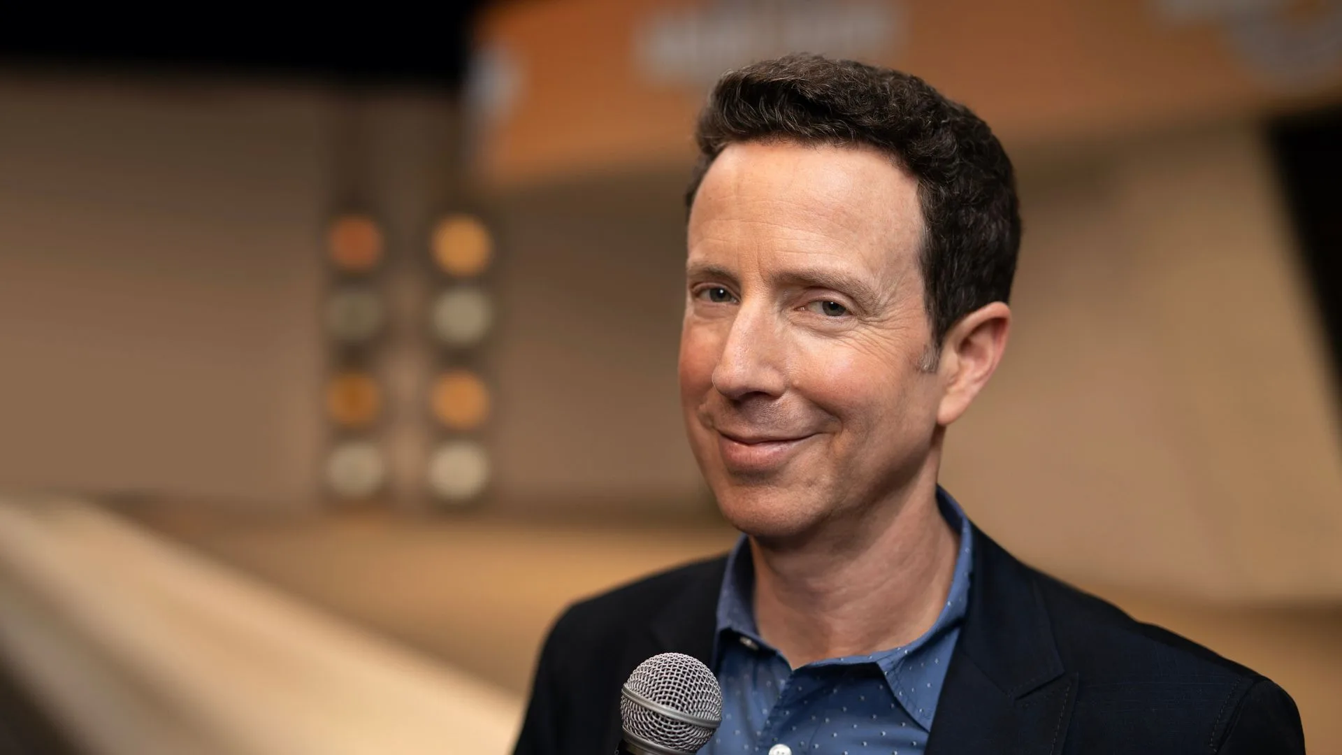 Adam Growe holding a microphone at a corporate event