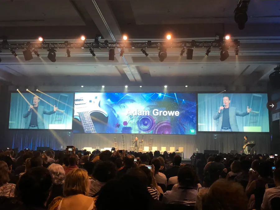 Adam Growe hosting on a conference main stage before a full ballroom